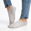 Gray no-show socks worn with blue jeans on a white background