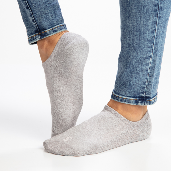 Gray no-show socks worn with blue jeans on a white background