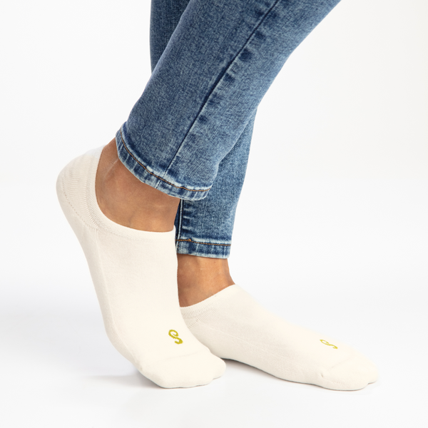 Natural cotton no-show invisible socks worn with blue jeans on a white background