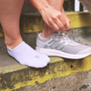 Person wearing hipSwan white organic cotton no-show invisible trainer socks on a concrete step.